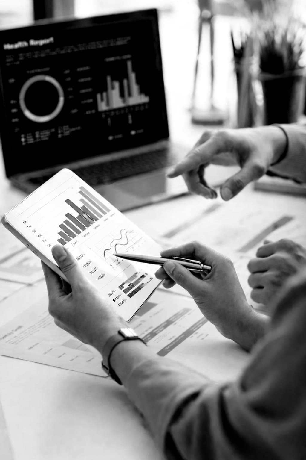 Business analytics dashboard - hands reviewing data charts on tablet with laptop in background